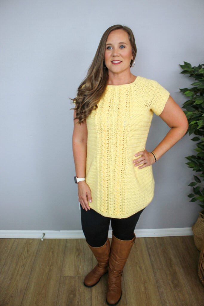 Woman wearing a yellow cabled crochet tunic, called the Aspen Tunic. 