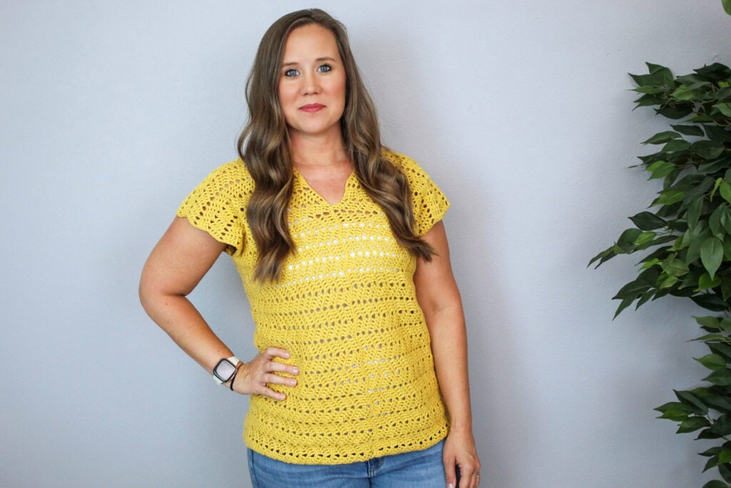 Woman wearing a yellow crochet V-Neck top, called the Chevy Tee.
