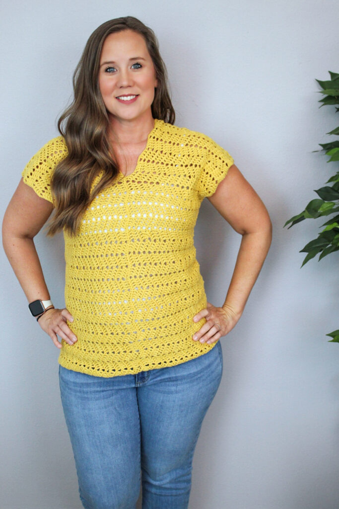 Woman wearing a yellow crochet V-neck top, called the Chevy Tee.