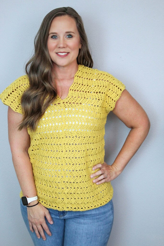 Woman wearing a yellow crochet v-neck top, called the Chevy Tee.