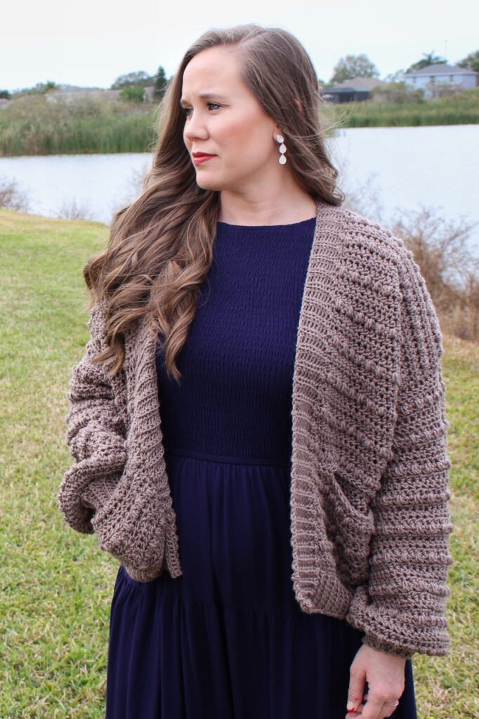 Woman wearing a crochet cardigan called the Pippa Pebble Cardigan.