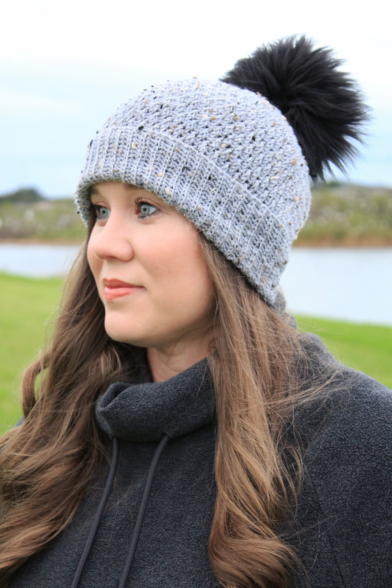 Dutton Beanie - Alpine Stitch Crochet Hat Pattern made in light gray with a black faux fur pom pom