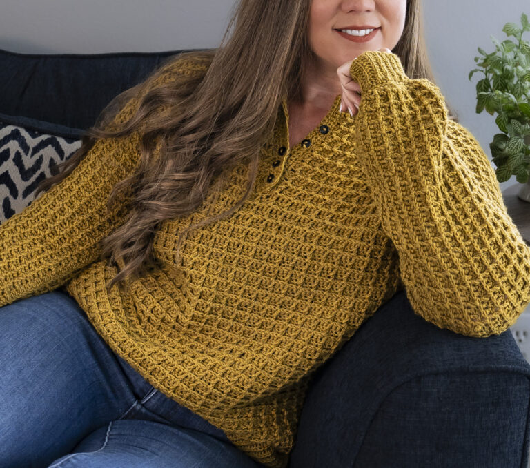 Woman wearing a yellow crochet henley sweater.