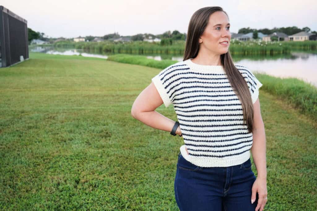 Woman wearing a short-sleeved crochet sweater, called the Peyton Sweater.